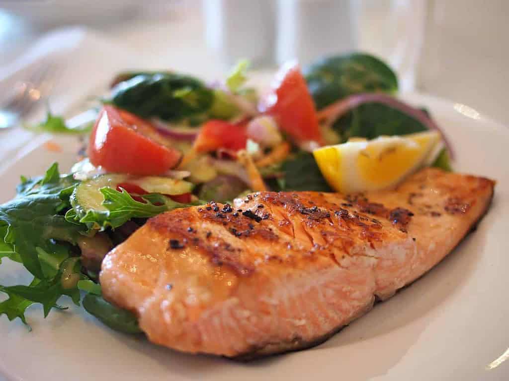 cooked salmon with vegetables and lemon on a plate
