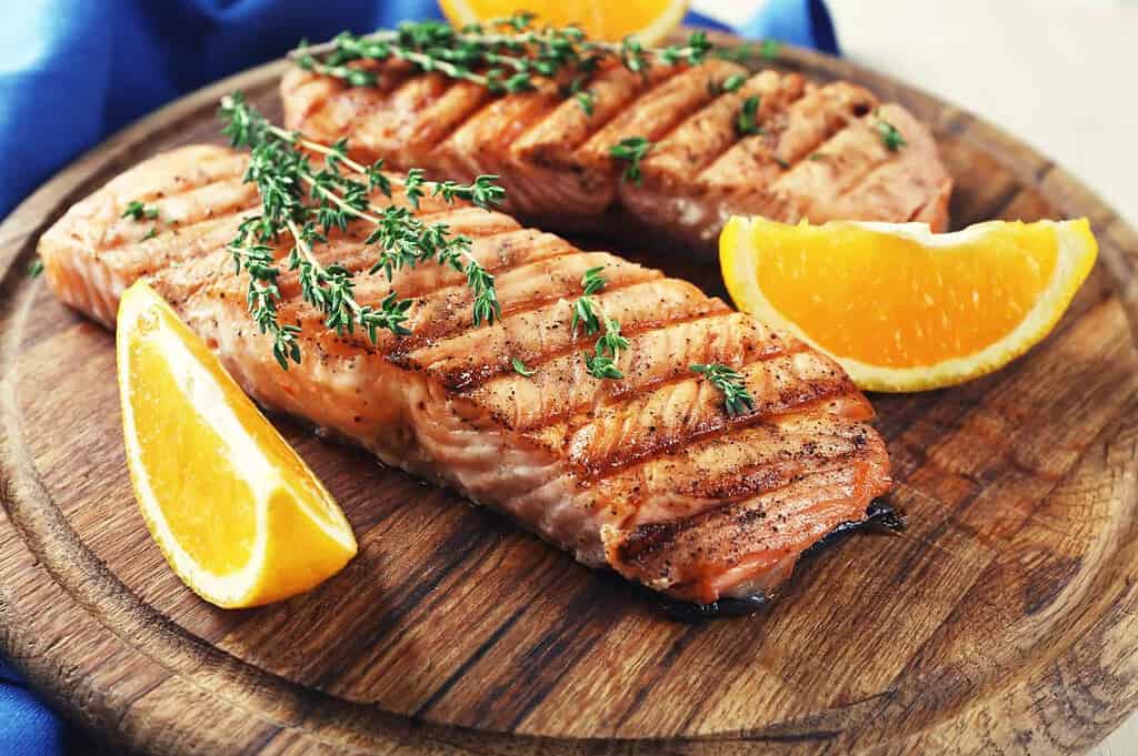 grilled salmon and orange slices on cutting board