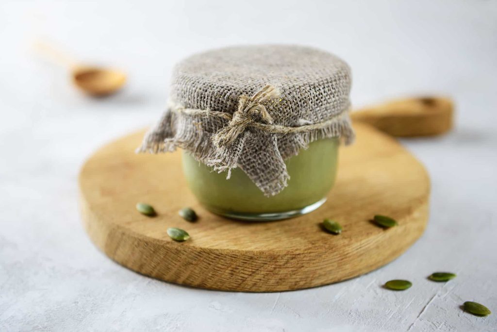 pumpkin urbech in a glass jar on a wooden board