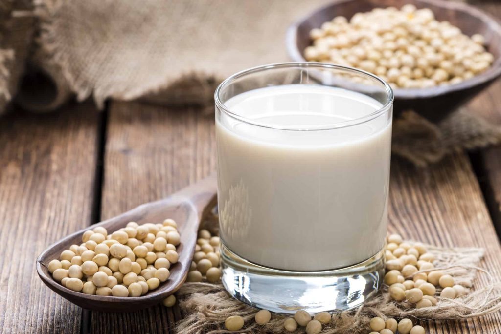 glass with soy milk and soy seeds on a table