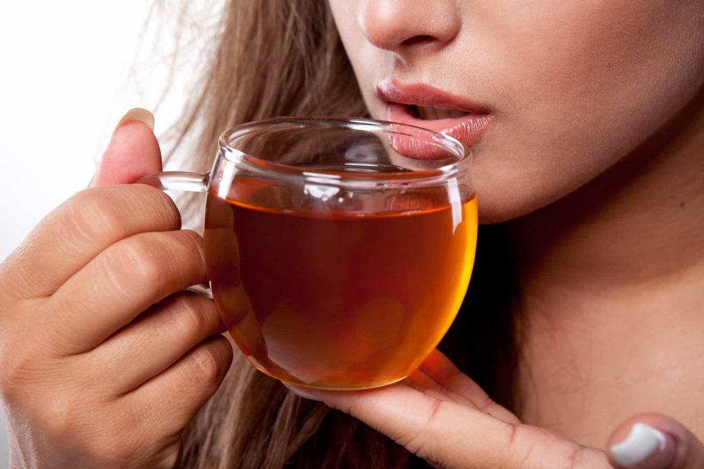Woman with cup of fresh tasty black tea