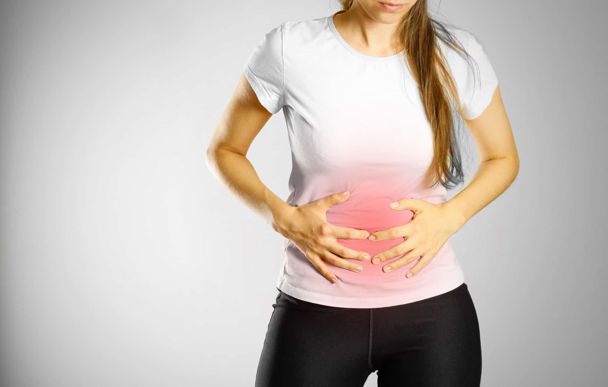 A woman sitting with her hands pressed against her stomach