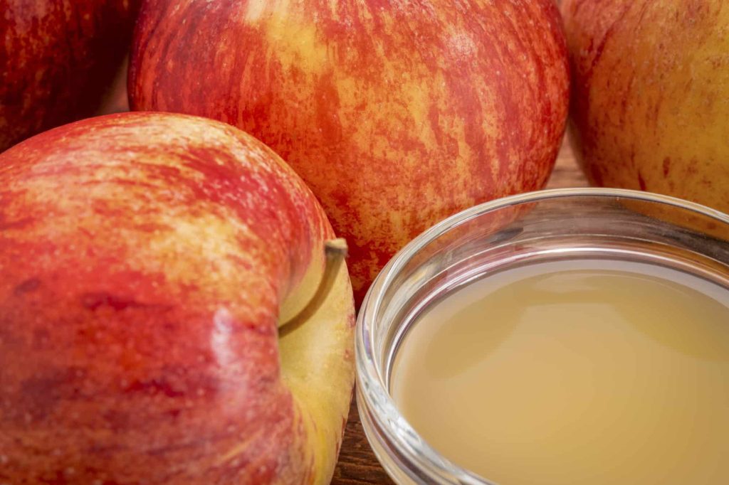 unfiltered, raw apple cider vinegar with fresh red apples