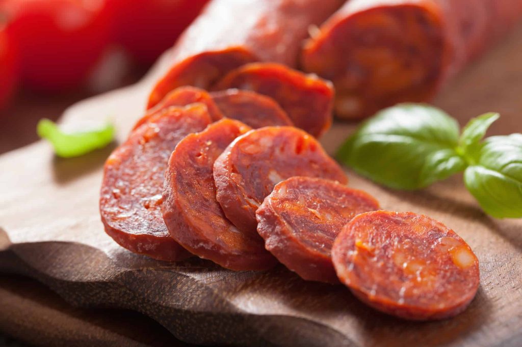 spanish chorizo sausage with basil on chopping board
