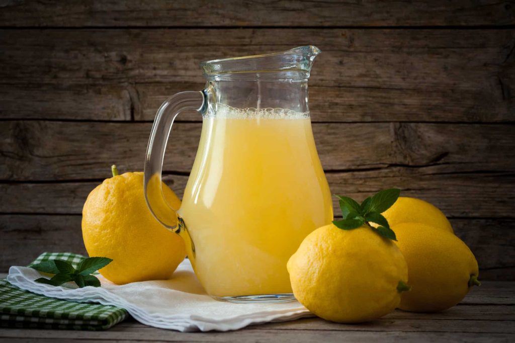 Jug with lemonade and fresh lemons