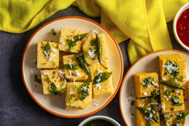 Dhokla, the light steamed chickpea cake from Gujarat, cut into squares and tempered with mustard seed.