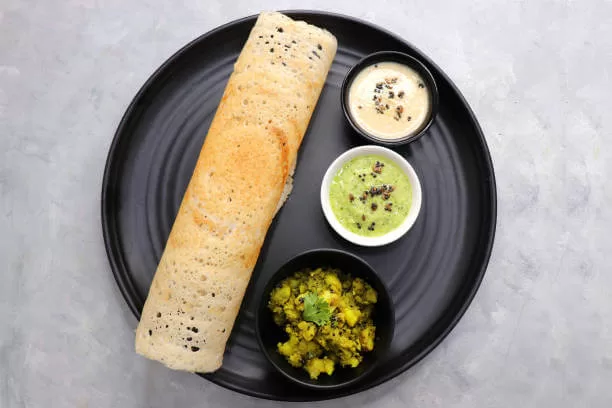 A masala dosa, the thin fermented rice pancake rolled around spiced potato, with chutney and sambar.