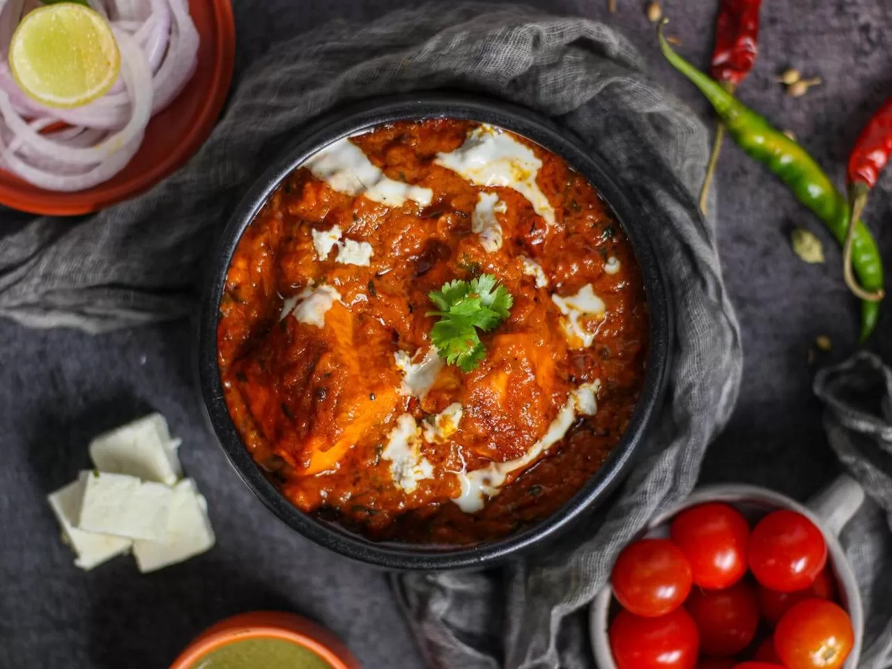 Butter chicken, pieces of chicken in a creamy tomato sauce, served with naan.
