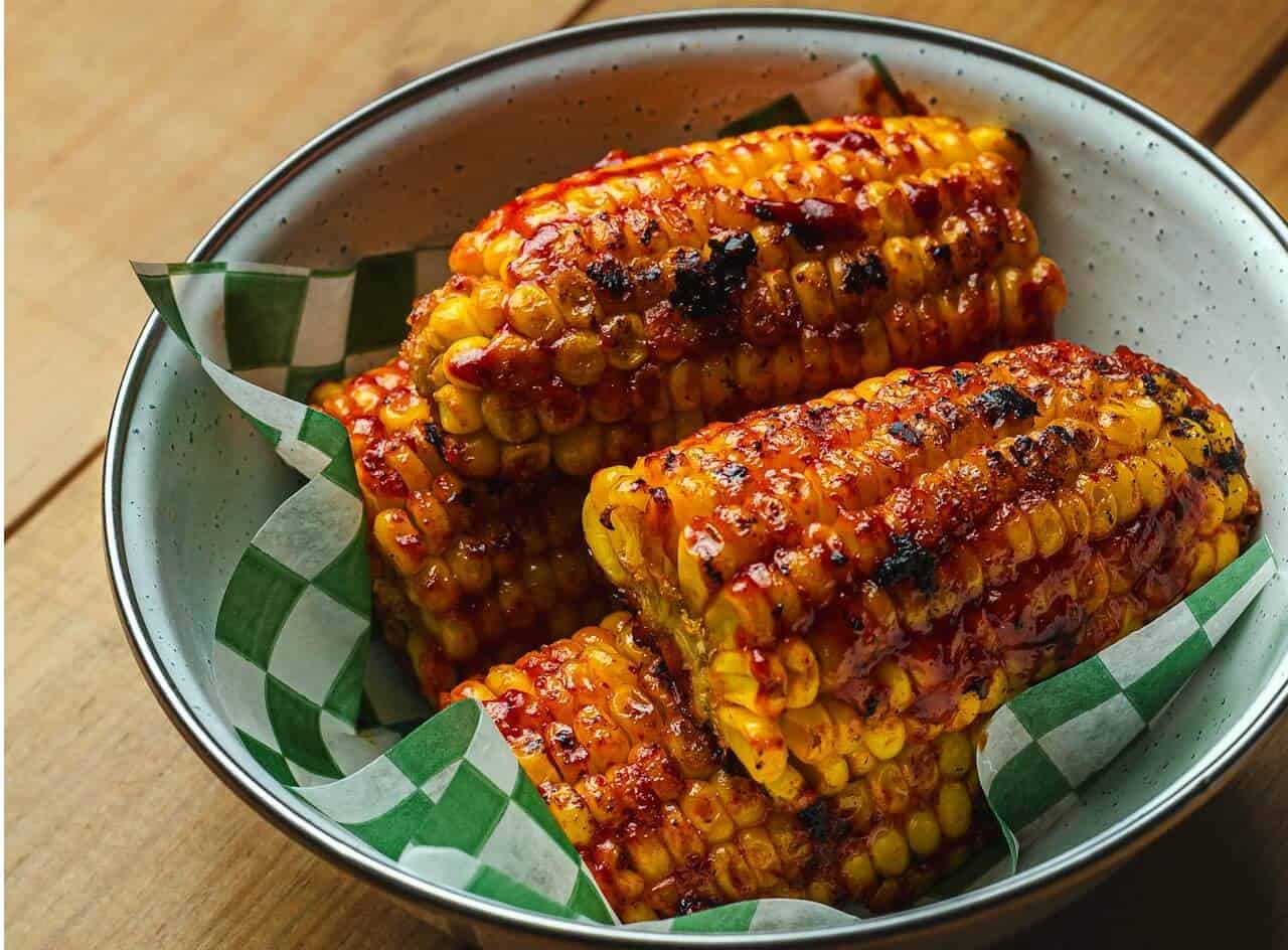 Elote, Mexican street corn on the cob, grilled and coated in mayonnaise, cheese and chilli powder.