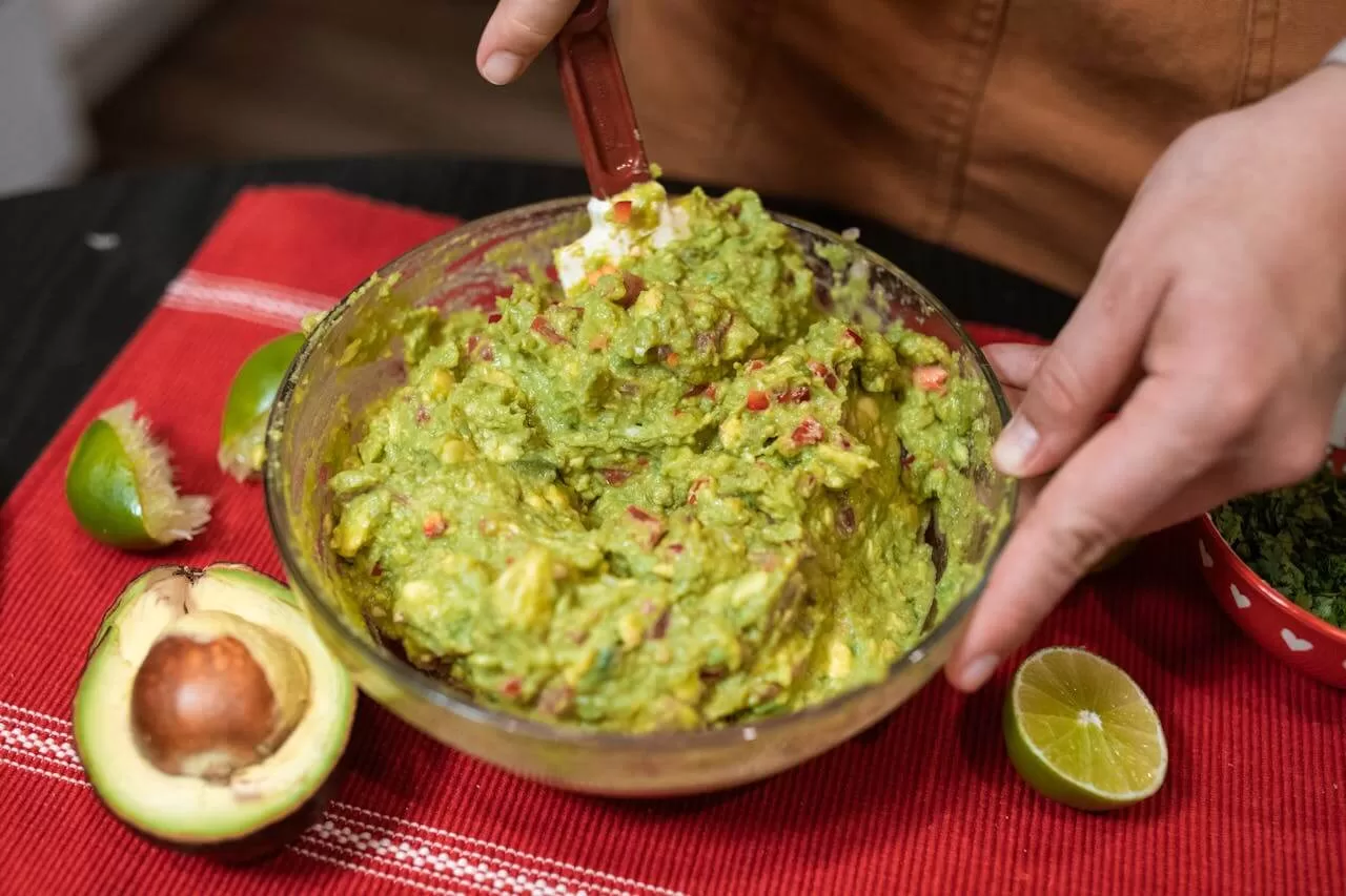 Guacamole in a stone bowl, mashed avocado flecked with coriander and lime, served with corn chips.