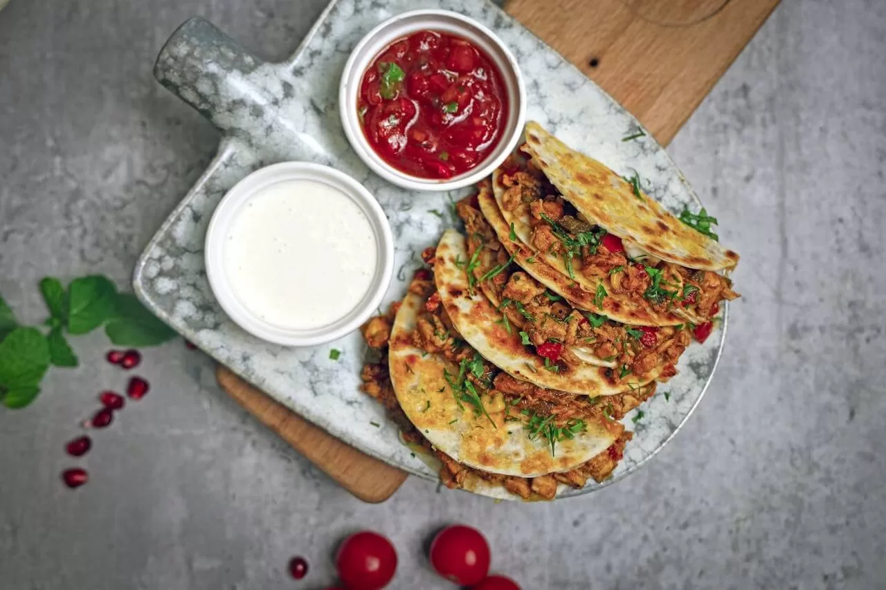 Quesadillas cut into wedges, the melted cheese filling pulling apart between the folded tortillas.