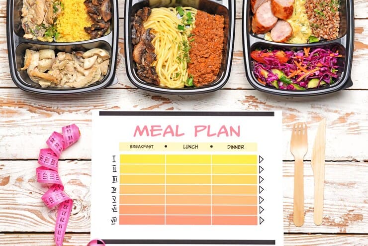On a wooden table, a meal plan highlights gluten-free vegan meals in organized containers. A feast of healthy choices is presented.