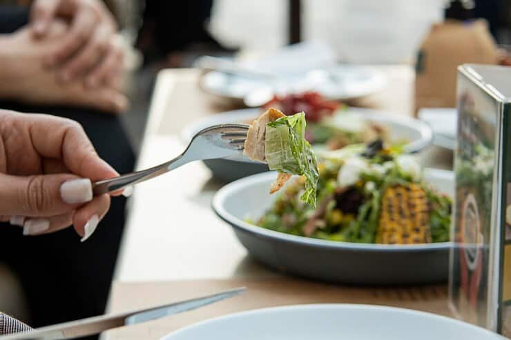A person enjoying a fresh salad with a fork at a gluten-free restaurant, highlighting healthy dining options.