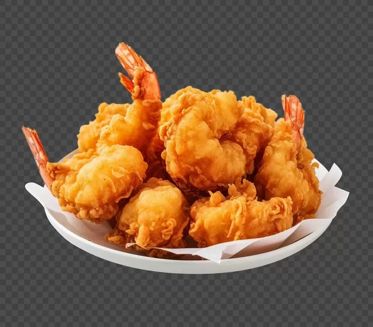 A plate of golden brown, crispy popcorn shrimp with tails is arranged on white parchment paper against a transparent background, perfect for those craving a paleo-friendly delight.