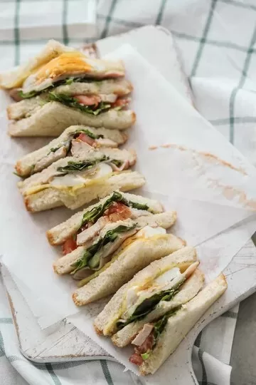 A row of stacked scallop bacon sandwiches on a white napkin.