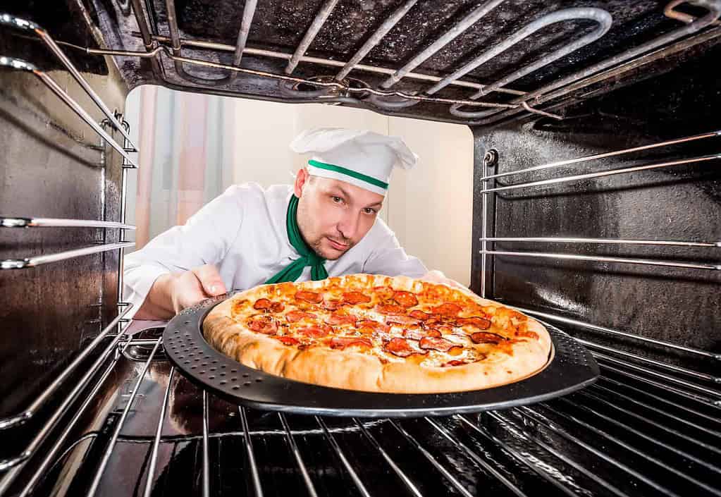 chef placing pizza in an oven to keep it warm