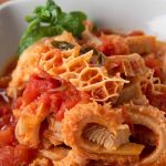 A close-up of a dish featuring Shaki meat in a tomato-based sauce, garnished with fresh herbs. The tripe's unique texture is highlighted, ensuring it's both visually appealing and safe food to enjoy, served in a white bowl.