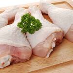 Raw chicken drumsticks and drumettes are artfully arranged on a wooden board, garnished with a bunch of fresh parsley on top, showcasing the subtle differences in size and shape between these two cuts.