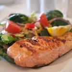 salmon with vegetables and lemon on a plate