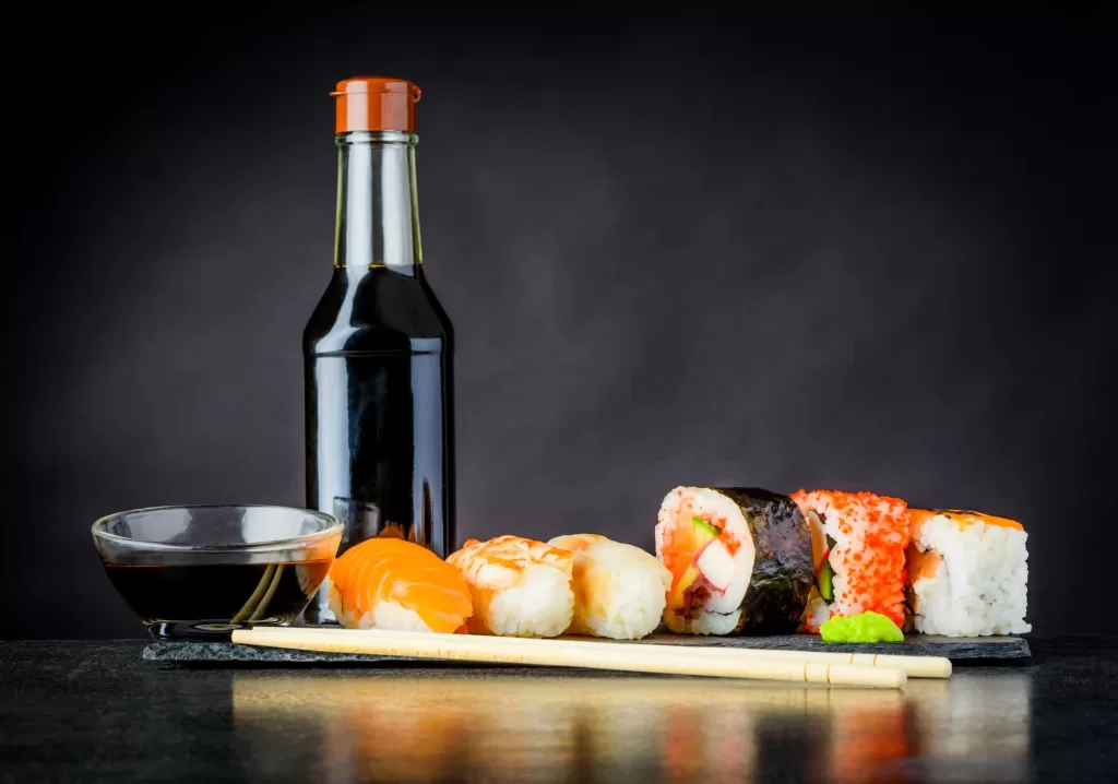 a bottle of soy sauce with sushi rolls