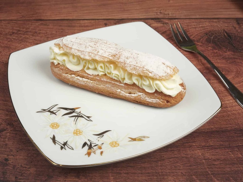 eclair with cream inside on a plate