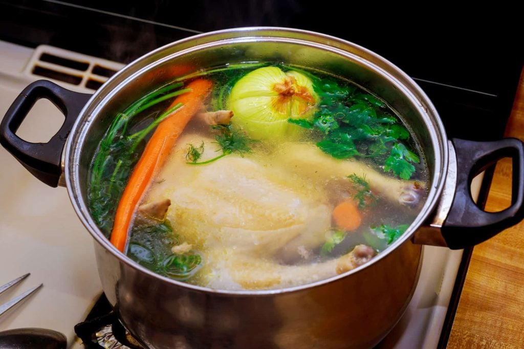 simmering chicken soup with vegetables in a pot