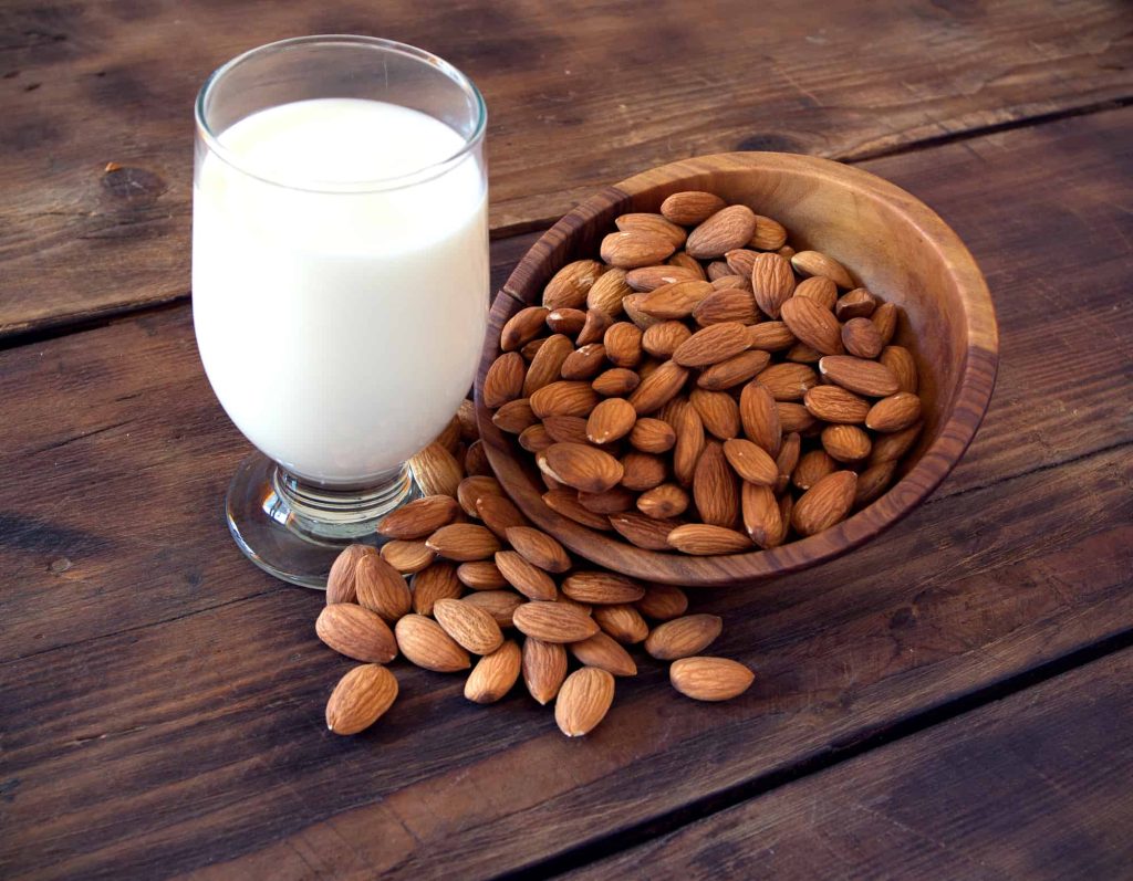 Almond milk in glass with almonds