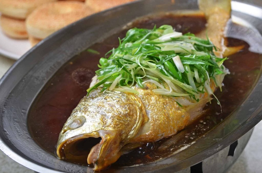 braised yellow croaker in soy sauce on white plate