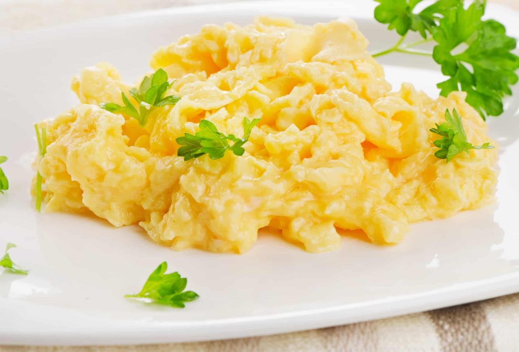 scrambled eggs with herbs on a white plate