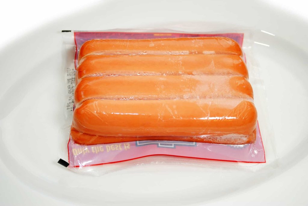 Thawing Frozen Packaged Hotdogs on a Plate