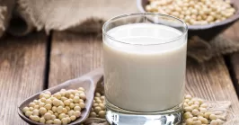 glass with soy milk and soy seeds on a table