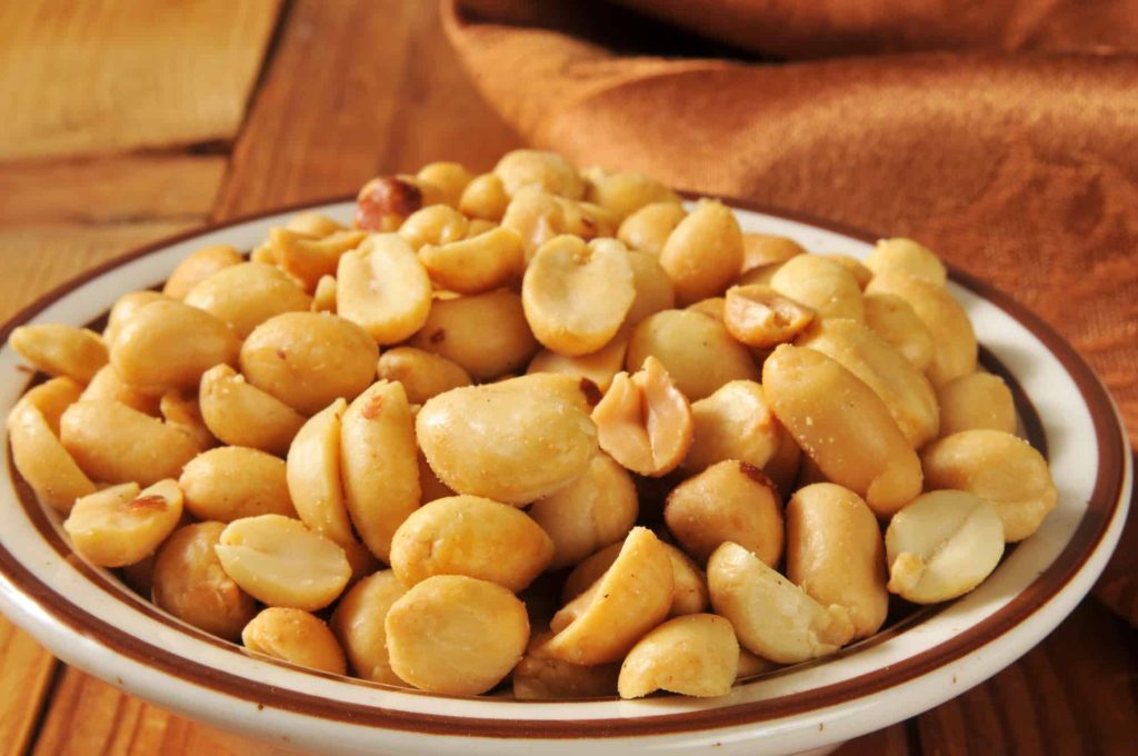 a bowl of roasted and salted peanuts on a plate