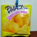 A yellow potato chips bag labeled "Potato Chips" with "Plain Salted Flavor" written underneath is clipped to a surface with a blue clothespin. For optimal potato chip storage, use a clip to keep your 2.12 oz (60g) bag fresh longer.