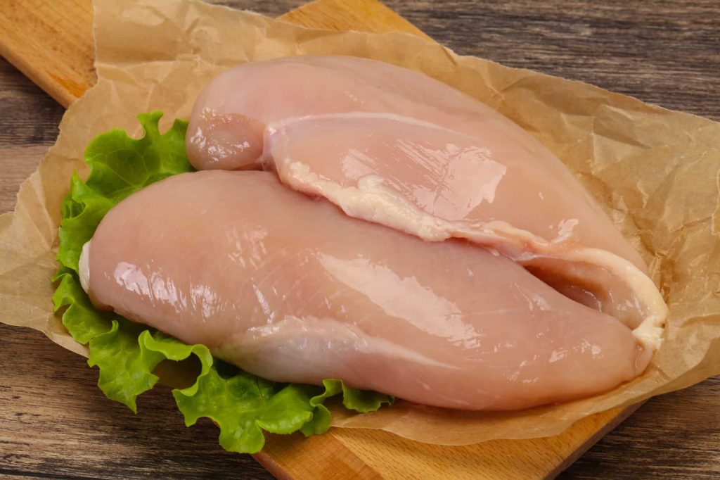 two raw chicken breast on a cutting board ready for cooking with no red spots