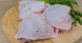 raw chicken thighs with lettuce on a cutting board