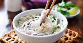 picking up vermicelli noodles out of a bowl of pho