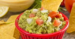 pico de gallo added to guacamole in a bowl