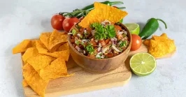 a bowl of pico de gallo with parsley and other ingredients on a cutting board