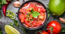 pico de gallo in a bowl and ingredients on a table