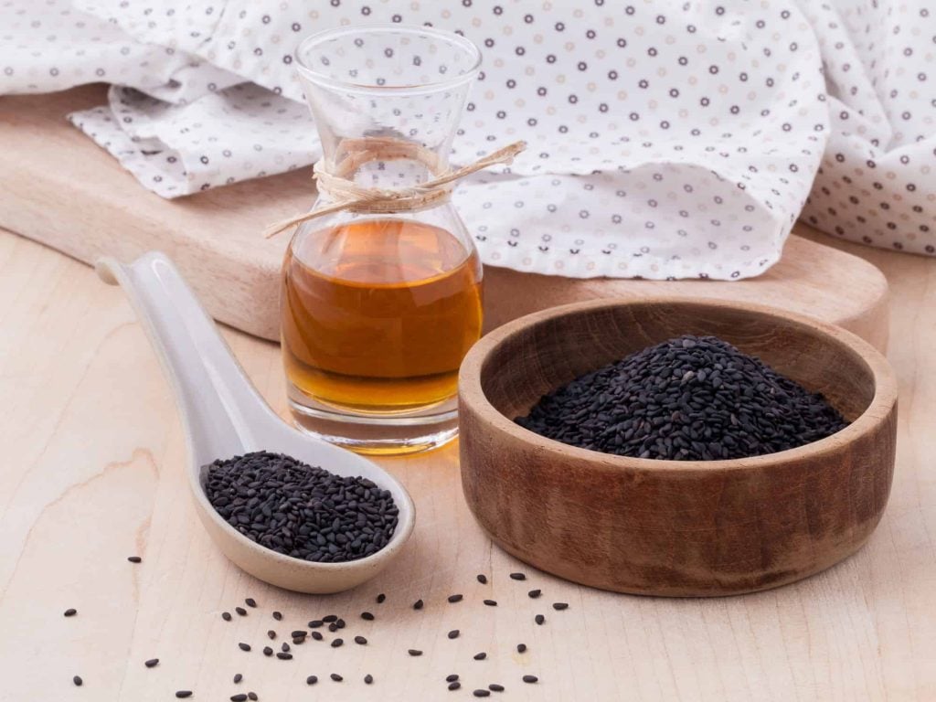 Black sesame oil and sesame seeds on wooden table