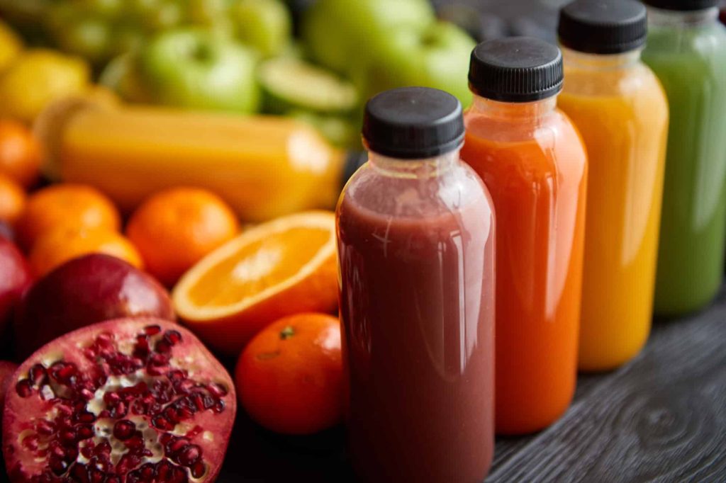 bottles filled with fresh fruit Placed on black wooden table.