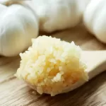 minced garlic on a wooden spoon