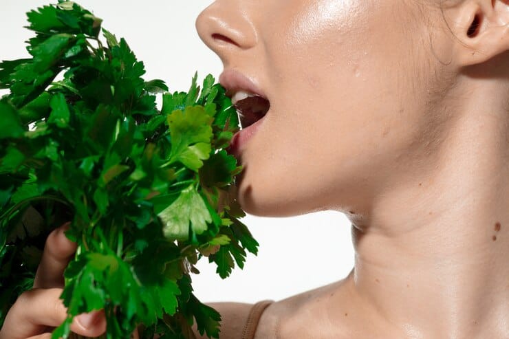 A woman enjoys a variety of fresh herbs, highlighting the benefits of a vegan diet for managing eczema.