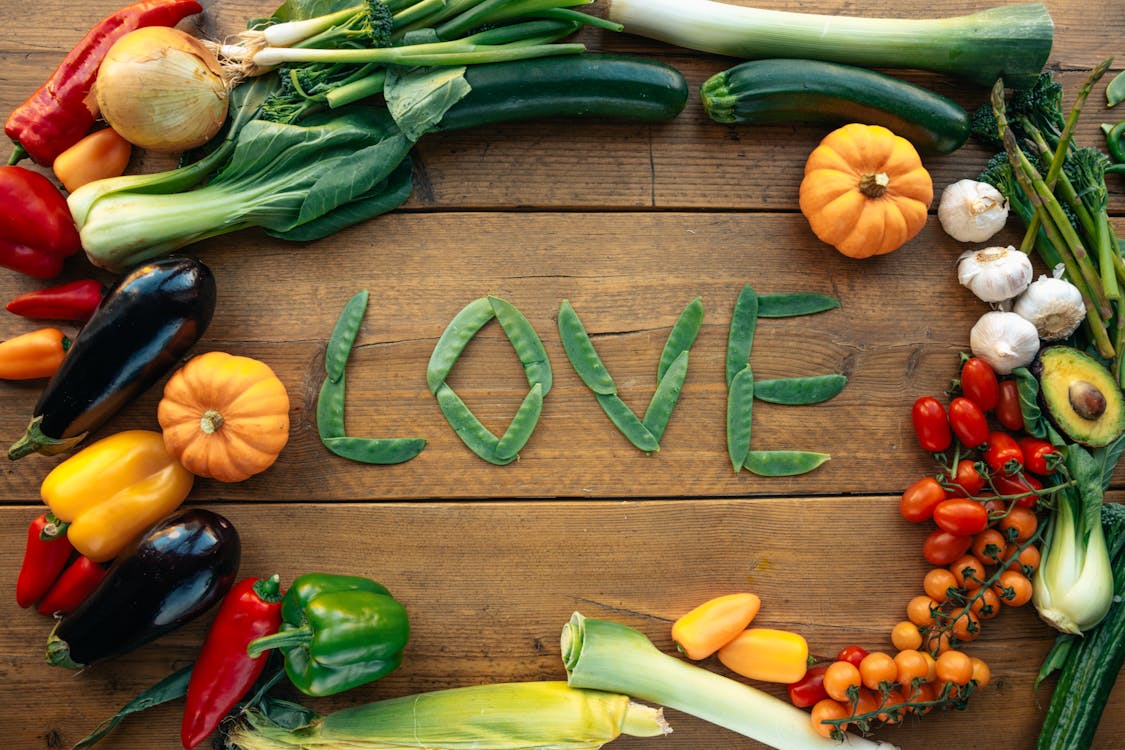  A colorful arrangement of vegetables and fruits in a circle, with the word "love" artistically placed in the center.