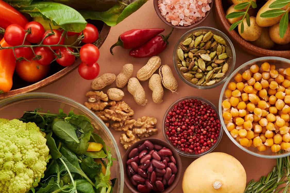 A colorful assortment of fruits and vegetables displayed in bowls, promoting a vegan diet for optimal digestive health.