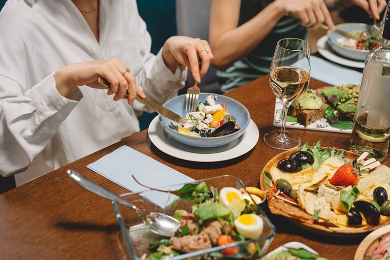 A diverse group of individuals enjoying a vegan meal together at a table, promoting a healthy digestive system.