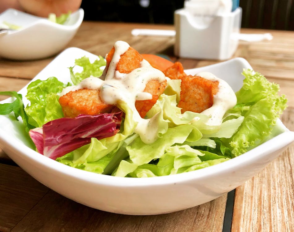 A white bowl filled with fresh green lettuce and crispy croutons, ready to be enjoyed.