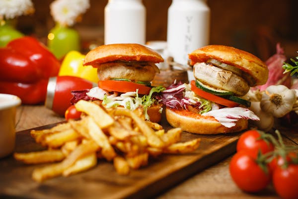 Two delicious burgers and a side of crispy French fries on a rustic wooden cutting board. Perfect for a hearty meal.