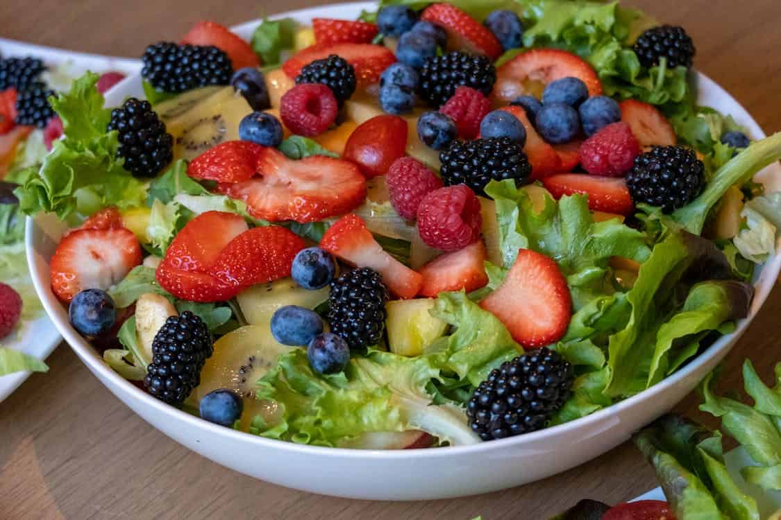 A vibrant bowl of salad featuring an assortment of berries and fruits, promoting a vegan diet for digestive health.