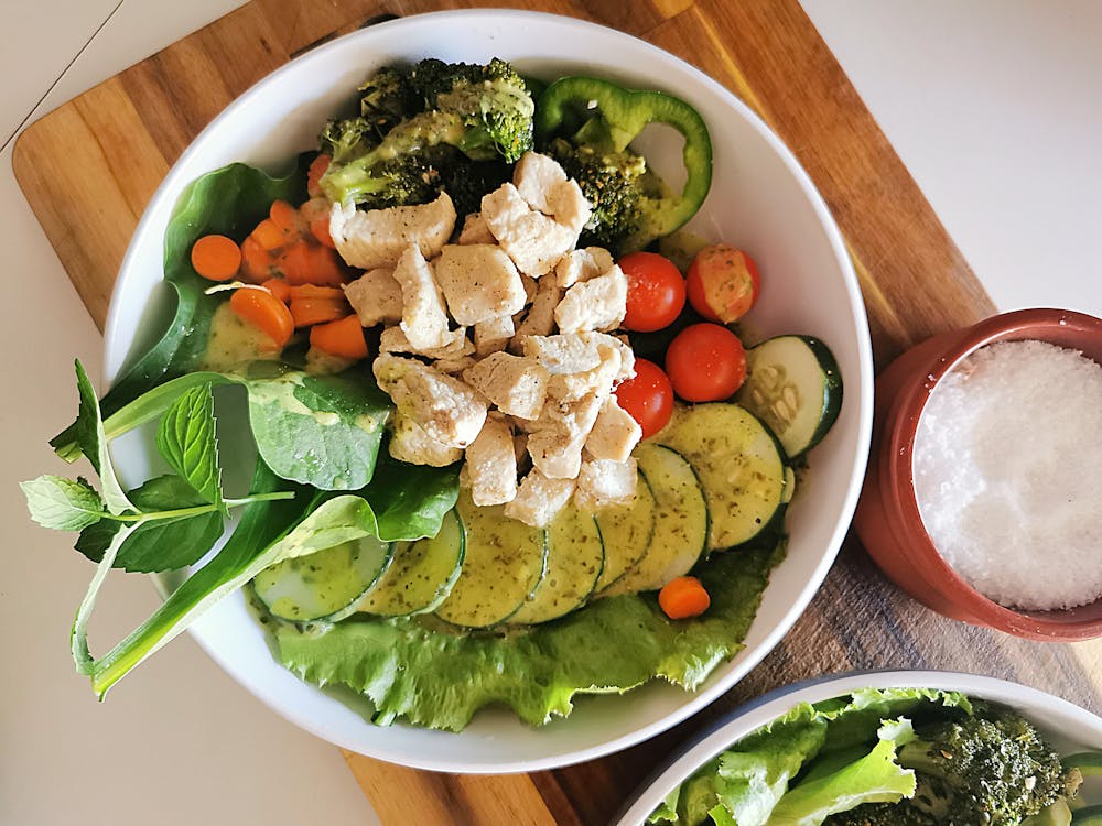 A colorful bowl of salad featuring chicken, broccoli, carrots, and a variety of fresh vegetables. Healthy and appetizing meal option.